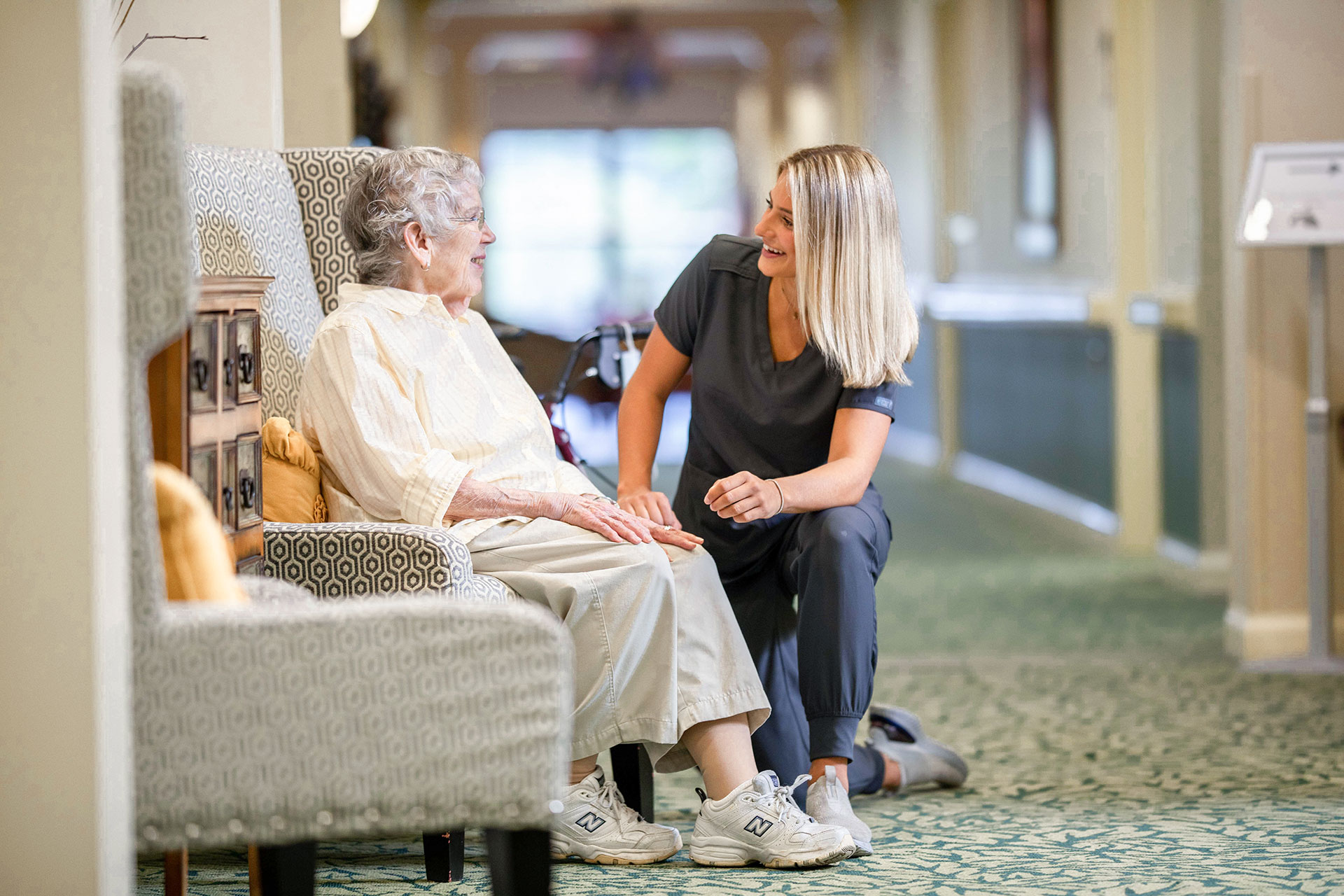 The Oaks at Bartlett | Senior woman sitting in hallway with associate