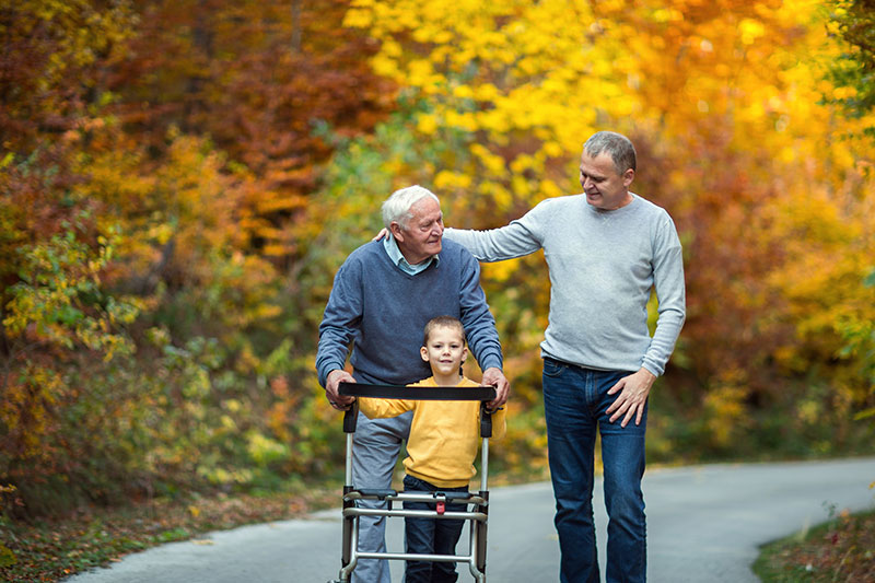 The Oaks at Bartlett | Senior man walking on trail with family