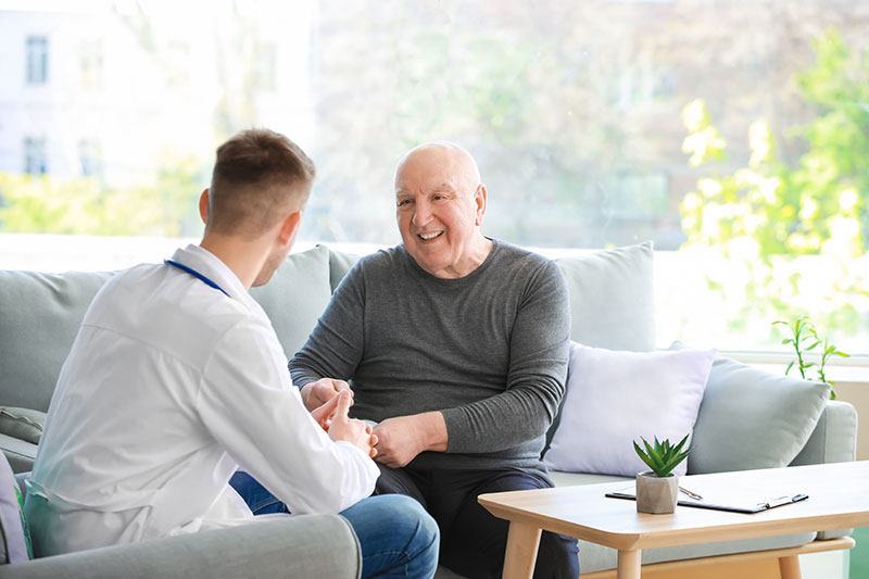 The Oaks at Bartlett | Senior talking to his caregiver while sitting on a couch