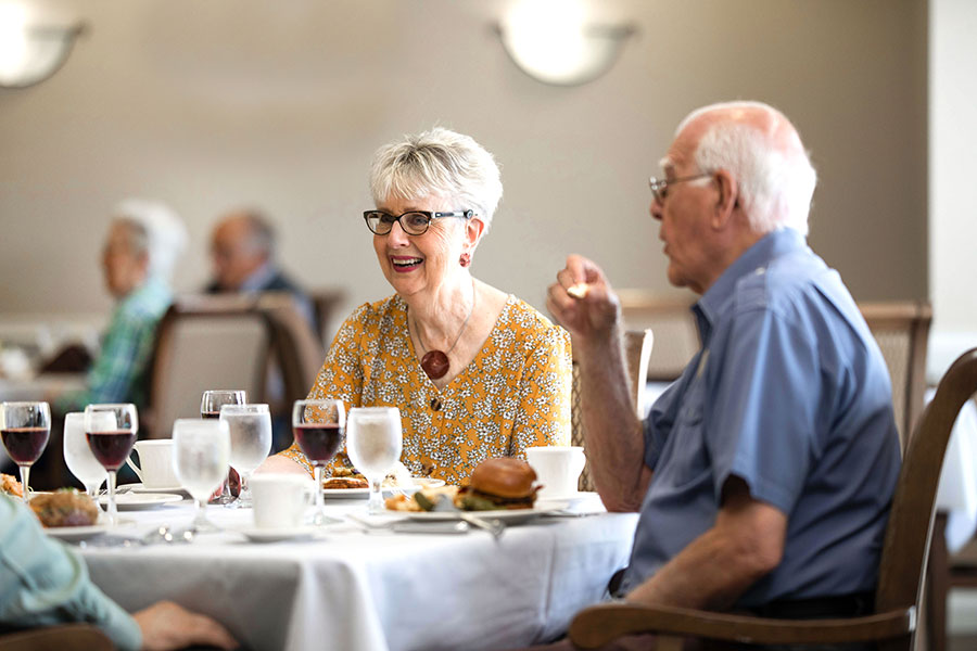 The Oaks at Bartlett | Group of happy seniors having some wine at the dining room table