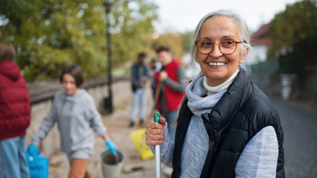 woman participating in one of the many volunteering opportunities for seniors by cleaning up parks